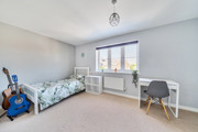 Bedroom with single bed, desk by window, and blue guitar on the floor.