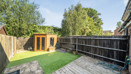Rear garden with decking, lawn, trees, and wooden outbuilding.