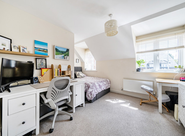 Bedroom with bed, desk, storage units and window.