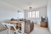 Living room with sofa, dining table with chairs, TV and window.