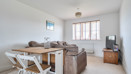 Living room with sofa, dining table with chairs, TV and window.