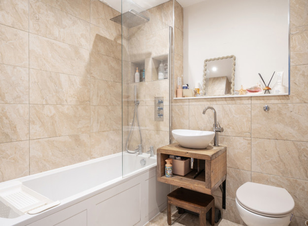 Bathroom with bathtub, glass shower screen, sink and toilet.