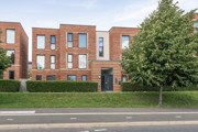 Apartment building with landscaped grounds and a tree beside the entrance.