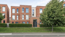 Apartment building with landscaped grounds and a tree beside the entrance.