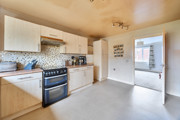 Kitchen with wooden cabinets, tiled floor, and freestanding cooker near a internal door.