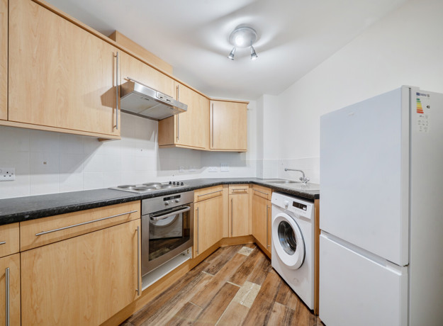 Kitchen with cabinets, oven, washing machine and fridge freezer.