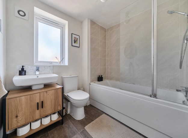 Bathroom with bathtub, shower screen, sink unit, toilet, and frosted window.