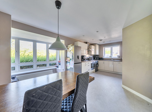 Open plan dining and kitchen area with neutral flooring and garden views