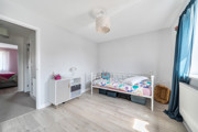 Children's bedroom with single bed, cupboard, and window with curtain.