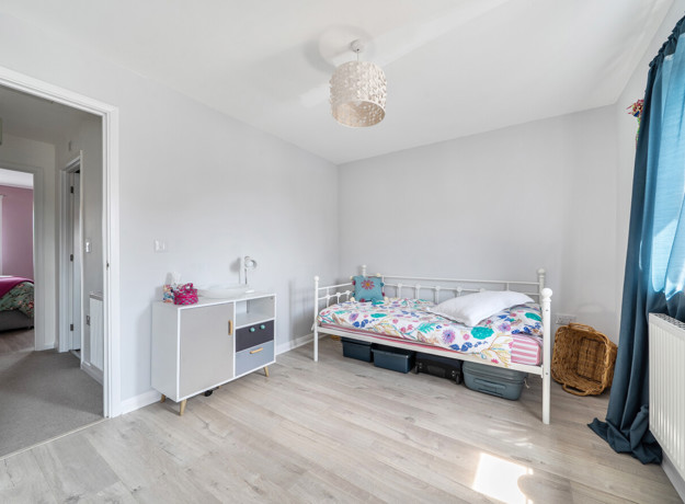 Children's bedroom with single bed, cupboard, and window with curtain.