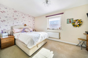 Bedroom with double bed, bedside tables, patterned wallpaper and neutral décor