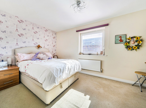 Bedroom with double bed, bedside tables, patterned wallpaper and neutral décor