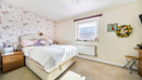Bedroom with double bed, bedside tables, patterned wallpaper and neutral décor