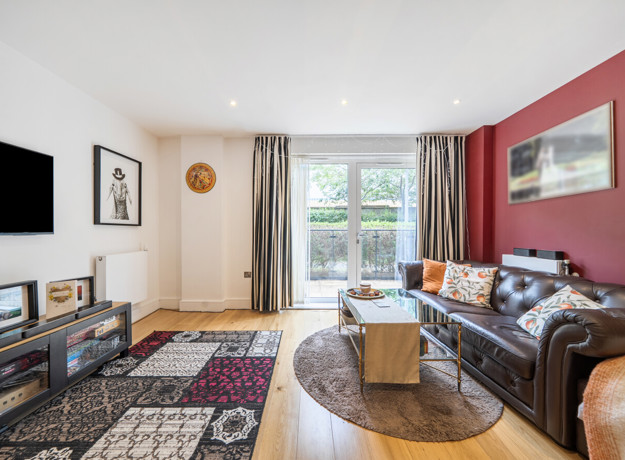 Living room with sofas, rug, television, and patio doors.