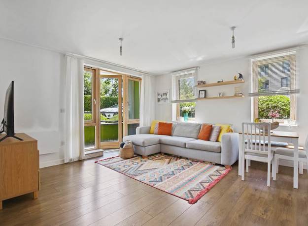 Living area with sofa, table, TV unit, and glass doors to outside.