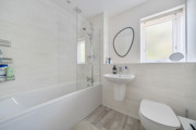 Bathroom with bathtub and shower, toilet, wall-mounted sink and tiled walls