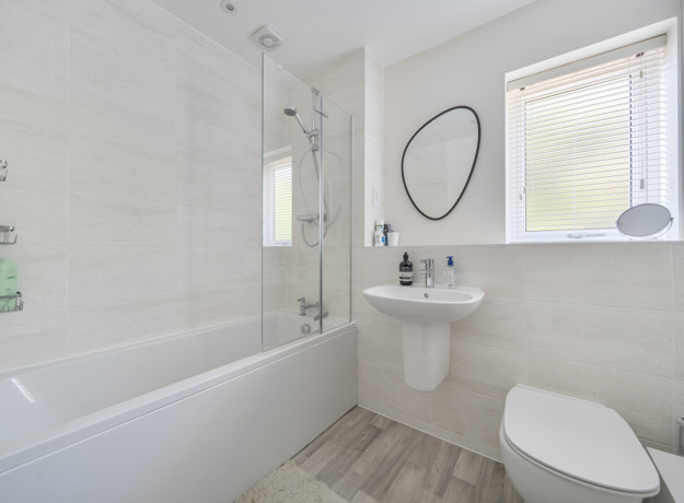 Bathroom with bathtub and shower, toilet, wall-mounted sink and tiled walls