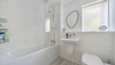 Bathroom with bathtub and shower, toilet, wall-mounted sink and tiled walls