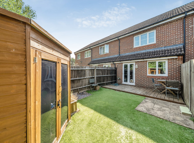 Rear garden with lawn, wooden shed, and fenced boundaries.