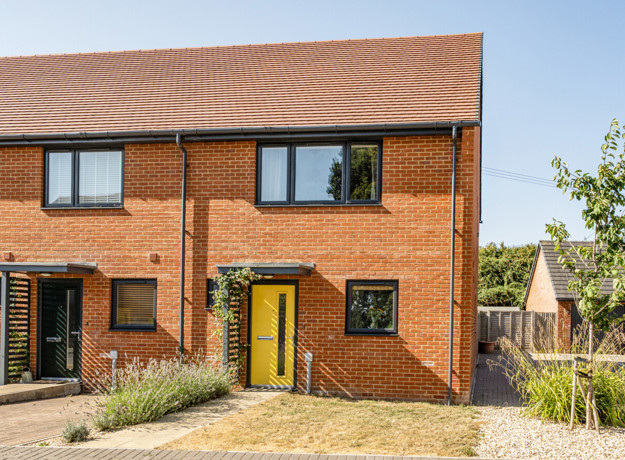 Front view of a two-storey brick house with a yellow front door and small front garden.