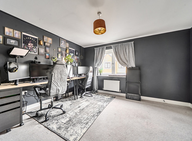 Home office or gaming room with desk, chair, computer screens and dark painted wall.