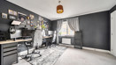 Home office or gaming room with desk, chair, computer screens and dark painted wall.