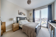 Bedroom with double bed, bedside tables, and window with curtains.