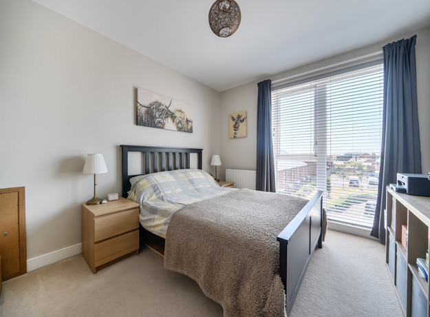 Bedroom with double bed, bedside tables, and window with curtains.