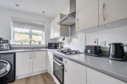 Kitchen with fitted cabinets, appliances and a window above the sink.