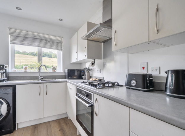 Kitchen with fitted cabinets, appliances and a window above the sink.