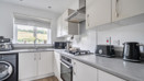 Kitchen with fitted cabinets, appliances and a window above the sink.