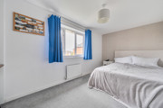 Bedroom with bed, window, radiator and light coloured walls.
