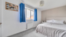 Bedroom with bed, window, radiator and light coloured walls.