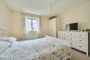 Bedroom with double bed, wardrobe, dresser, TV and window with curtains.