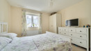 Bedroom with double bed, wardrobe, dresser, TV and window with curtains.