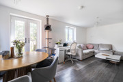 Open-plan living and dining area with table, chairs, sofas and patio doors.