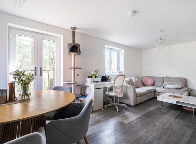 Open-plan living and dining area with table, chairs, sofas and patio doors.