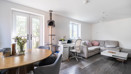 Open-plan living and dining area with table, chairs, sofas and patio doors.