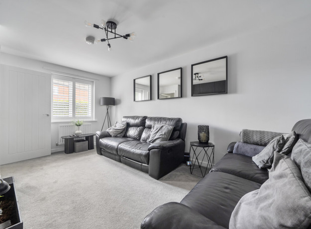 Living room with grey sofas, carpet, and framed pictures on wall.