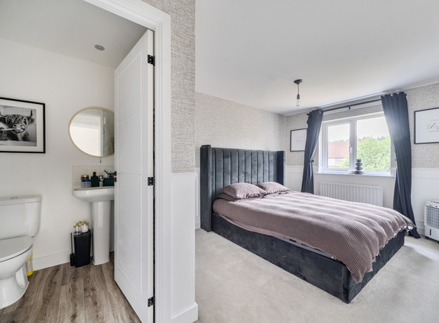 Bedroom with double bed, bedside tables, window with curtains and door into ensuite.