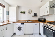 White kitchen with wooden-effect worktops and integrated appliances.