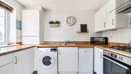 White kitchen with wooden-effect worktops and integrated appliances.