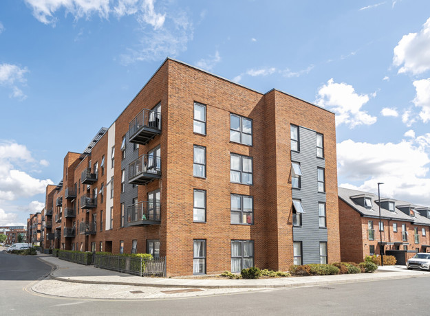 Exterior view of a brick apartment building on a street corner under blue skies.