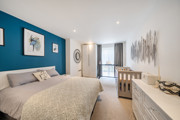 Bedroom with double bed, dresser, and window with curtains.