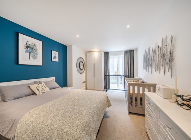 Bedroom with double bed, dresser, and window with curtains.