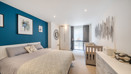 Bedroom with double bed, dresser, and window with curtains.