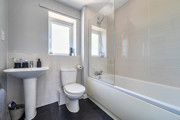 Modern bathroom with bathtub, wall tiles, toilet and sink