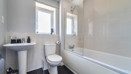 Modern bathroom with bathtub, wall tiles, toilet and sink