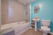 Family bathroom with bath and overhead shower, toilet, sink and tiled walls