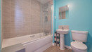Family bathroom with bath and overhead shower, toilet, sink and tiled walls